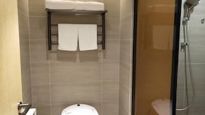Un baño con inodoro, toallero y toallas, y ducha.
