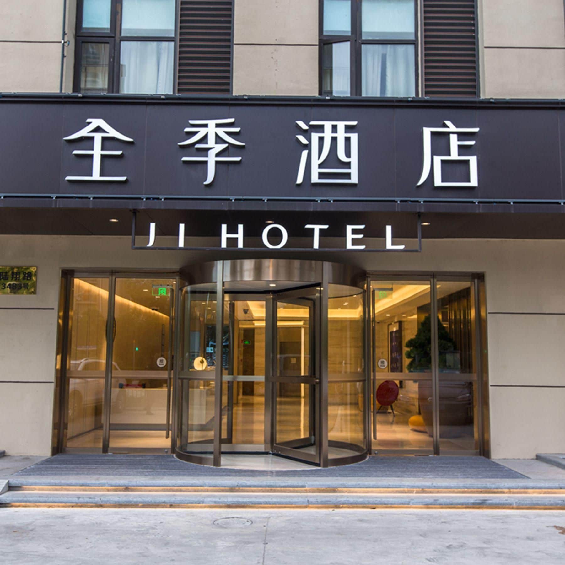 A hotel entrance with a revolving door and a sign above in both Chinese and English.