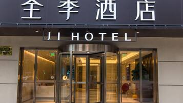 Ein Hotel Eingang mit einer Drehtür und einem Schild darüber, das auf Chinesisch und Englisch beschriftet ist.