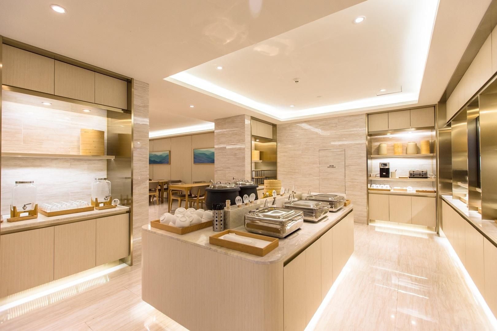 A modern kitchen with a central island, wooden cabinets, and a dining area in the background.