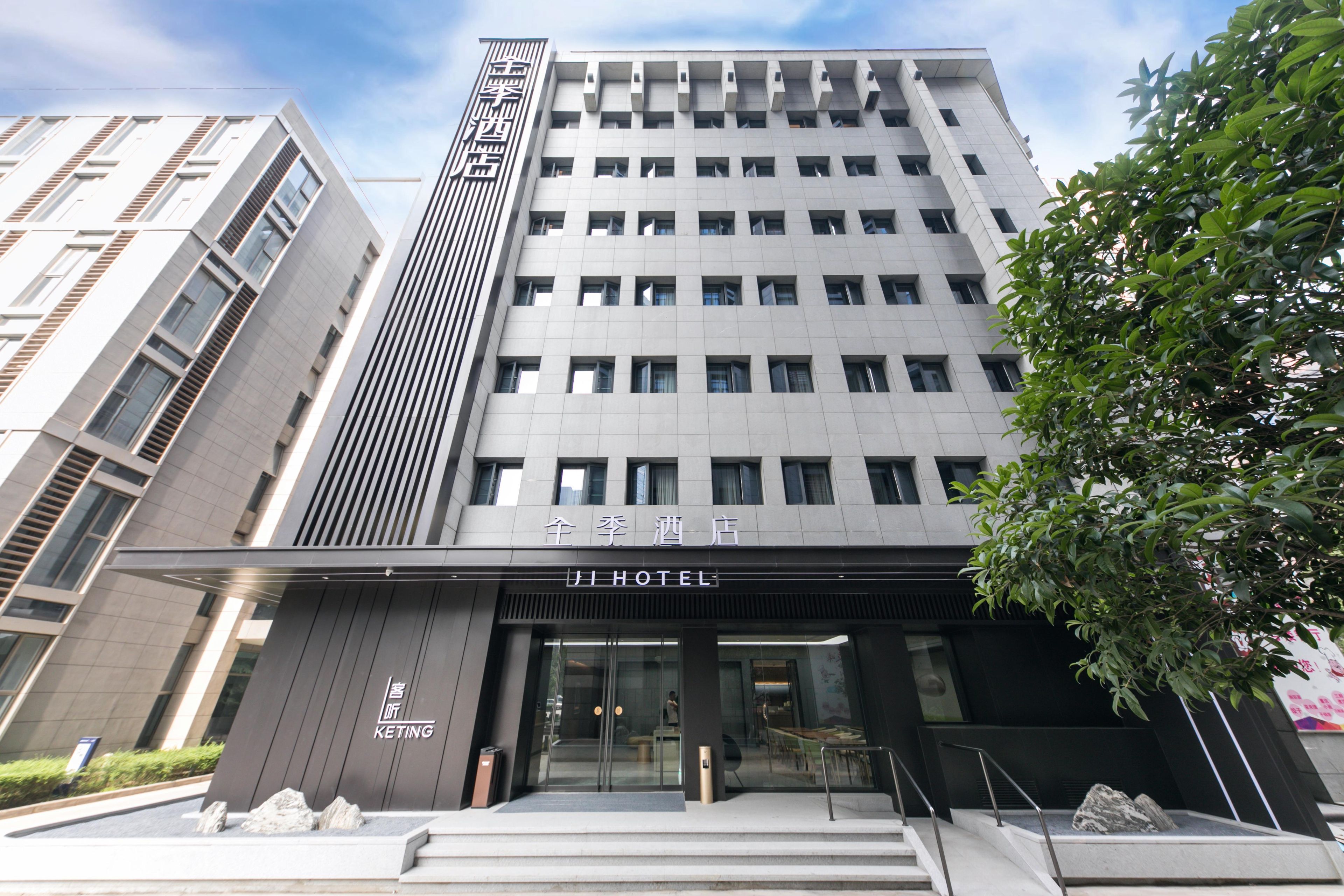 A modern hotel building with a prominent entrance, large windows, and a sign indicating it is a hotel.