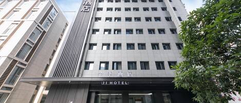 A modern hotel building with a prominent entrance, large windows, and a sign indicating it is a hotel.