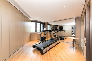 A modern gym with a treadmill, elliptical, and stationary bike, a small table, and a washing machine in the background. - Ji Hotel (xi'an Jinye Road, Shenzhou Digital Techn (Xi'an)