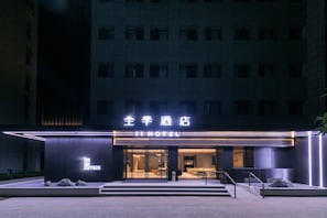 Un hotel amb façana moderna, cartelleria il·luminada i entrada visible.