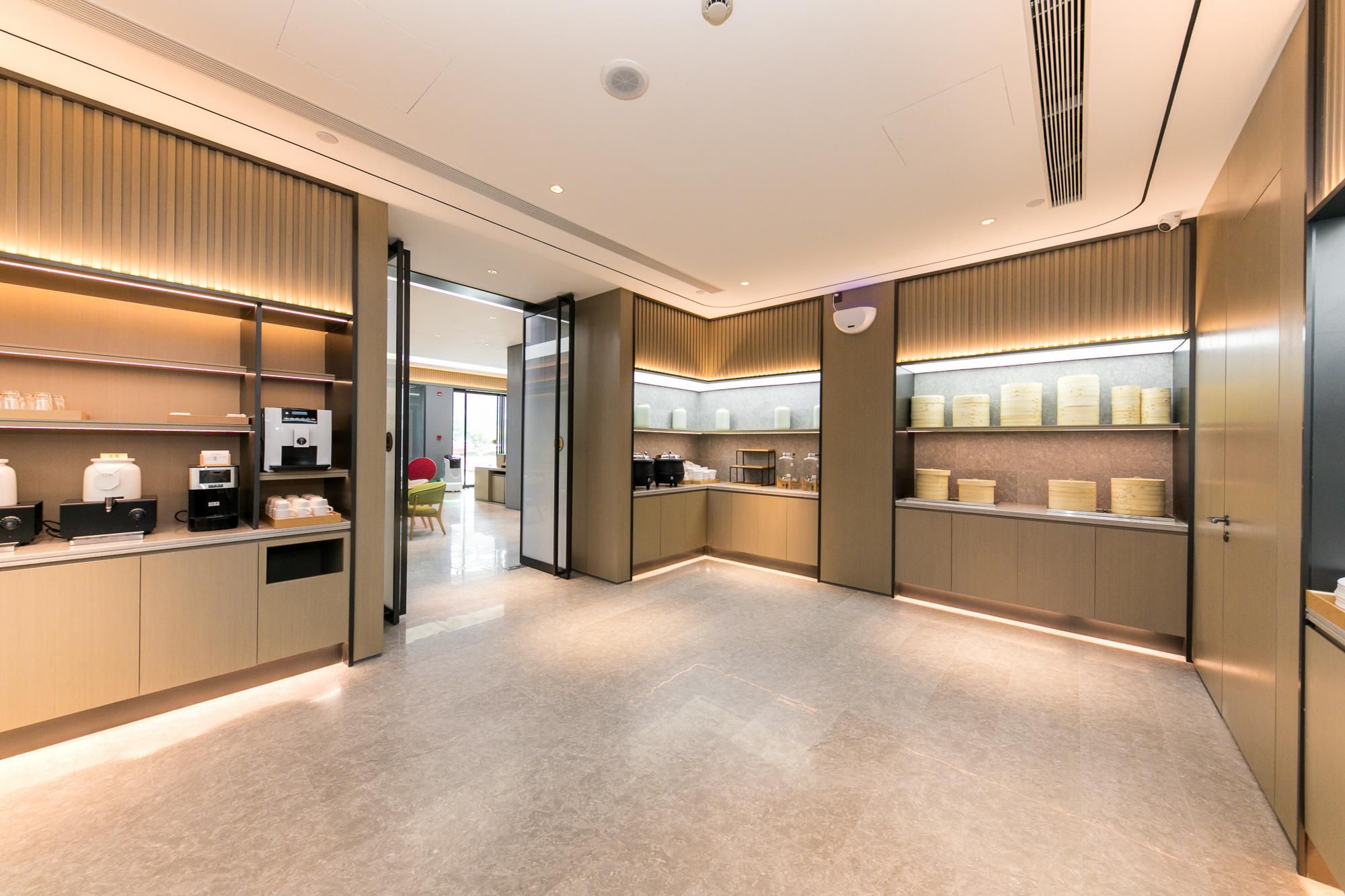 A modern hotel lobby with a clean, minimalist design, featuring a reception desk, seating area, and a view into the dining area.