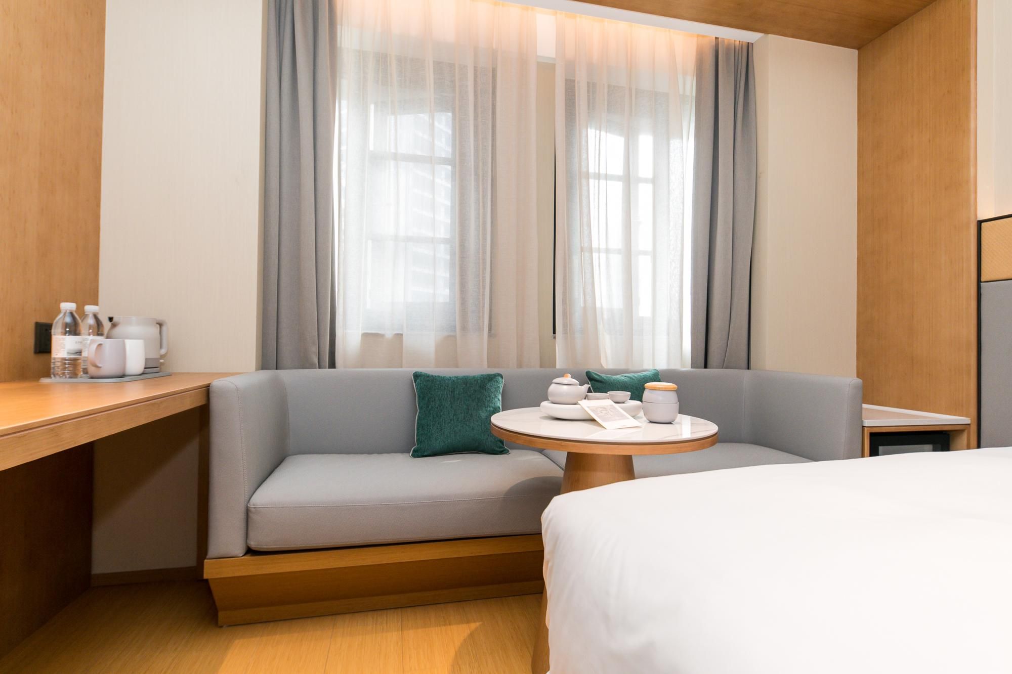 Una habitación de hotel con sofá, una pequeña mesa redonda con juego de té y una cama.
