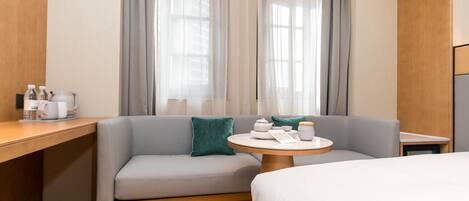 Una habitación de hotel con sofá, una pequeña mesa redonda con juego de té y una cama.