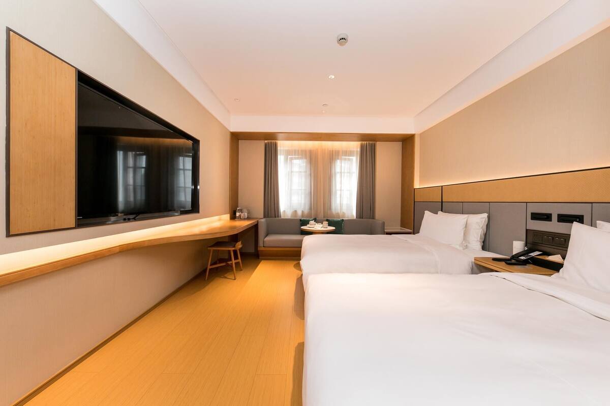 A hotel room with a bed, a desk, a chair, a television, and a window with curtains.