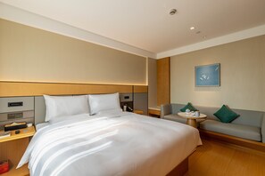 A hotel room with a large bed, a sofa, a small table, and a wall-mounted artwork. - Ji Hotel (xi'an Jinye Road, Shenzhou Digital Techn (Xi'an)
