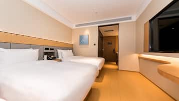 A hotel room with two beds, a bedside table with a phone, a small bedside table with a lamp, a window, and a door leading to another room.