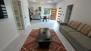 A modern living room with a sofa, a coffee table, and a dining area with chairs and a table. - Sequoia Retreat: BBQ, Patio, Near National Park (Three Rivers)
