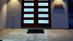 A building entrance with a double door, two wall-mounted lights, a nameplate, and a stone-paved ground. - Sequoia Retreat: BBQ, Patio, Near National Park (Three Rivers)