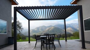 A covered patio with a table and chairs, overlooking a mountainous landscape. - Sequoia Retreat: BBQ, Patio, Near National Park (Three Rivers)