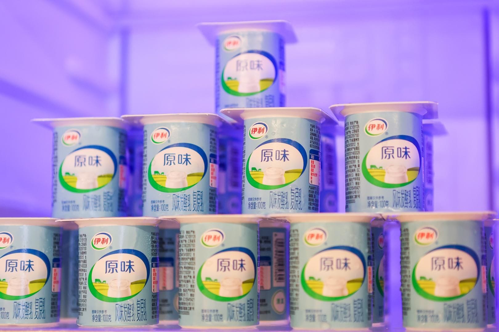 Vários recipientes de um produto com etiquetas em idioma estrangeiro, organizados em uma estrutura semelhante a uma pirâmide.