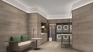 Un moderno cuarto de lavado con lavadora y secadora integradas, una mesita pequeña y un banco.