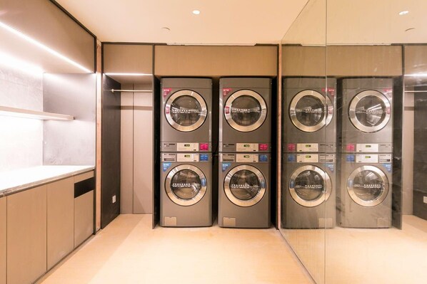 A row of four wall-mounted washing machines in a modern, well-lit laundry room with a minimalist design. - Ji Hotel (hangzhou West Lake Hubin Pedestrian Stre (Hangzhou)
