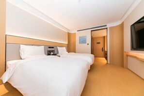 Ein Hotelzimmer mit zwei Betten, einem Nachttisch, einem Fernseher und einer Tür zu einem weiteren Raum.