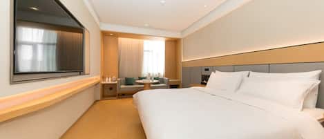 A hotel room with a large bed, a bedside table, a TV mounted on the wall, and a window with curtains.