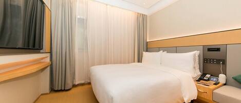 Habitación de hotel con cama, mesita de noche con teléfono, televisor sobre la cama y ventana con cortinas.