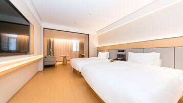 A hotel room with two beds, a TV, a desk, and a view of the city.