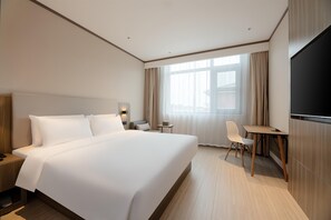 A hotel room with a large bed, a desk, a chair, a TV, and a window with curtains. - Hanting Hotel (xianyang International Airport Hote (Xianyang)