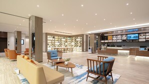 A modern hotel lobby with seating, a reception desk, a digital display, and a bookshelf. - Hanting Hotel (xianyang International Airport Hote (Xianyang)