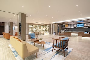 A modern hotel lobby with seating, a reception desk, a digital display, and a bookshelf. - Hanting Hotel (xianyang International Airport Hote (Xianyang)
