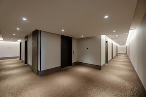 A long, narrow hallway with multiple doors, recessed ceiling lights, and carpeted floors. - Hanting Hotel (xianyang International Airport Hote (Xianyang)