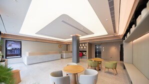 A modern hotel lobby with a reception desk, seating area, and a large digital display. - Ji Hotel Shanghai Jiangsu Road Subway Station (Shanghai)