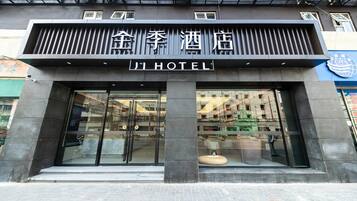 A hotel entrance with a modern facade, large glass doors, and a sign indicating it's a hotel.