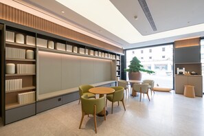 A modern interior with a seating area, bookshelves, and a large window. - Ji Hotel Shanghai Jiangsu Road Subway Station (Shanghai)