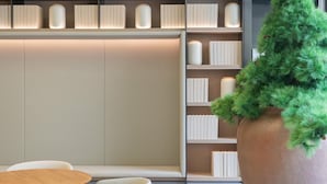A modern interior with a bookshelf, a round wooden table, and a large potted plant. - Ji Hotel Shanghai Jiangsu Road Subway Station (Shanghai)