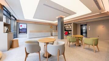 A modern lobby with a reception desk, seating area, and a large digital display.