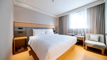 A hotel room with a large bed, bedside tables, a chair, and a window with curtains.