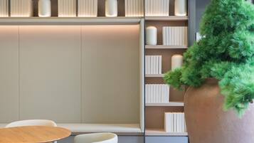 A modern interior with a bookshelf, a round wooden table, and a large potted plant.
