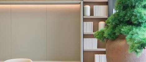 A modern interior with a bookshelf, a round wooden table, and a large potted plant.