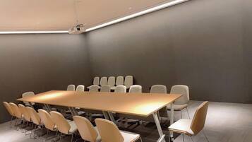 Una sala de conferencias con una larga mesa y varias sillas, equipada con un proyector.