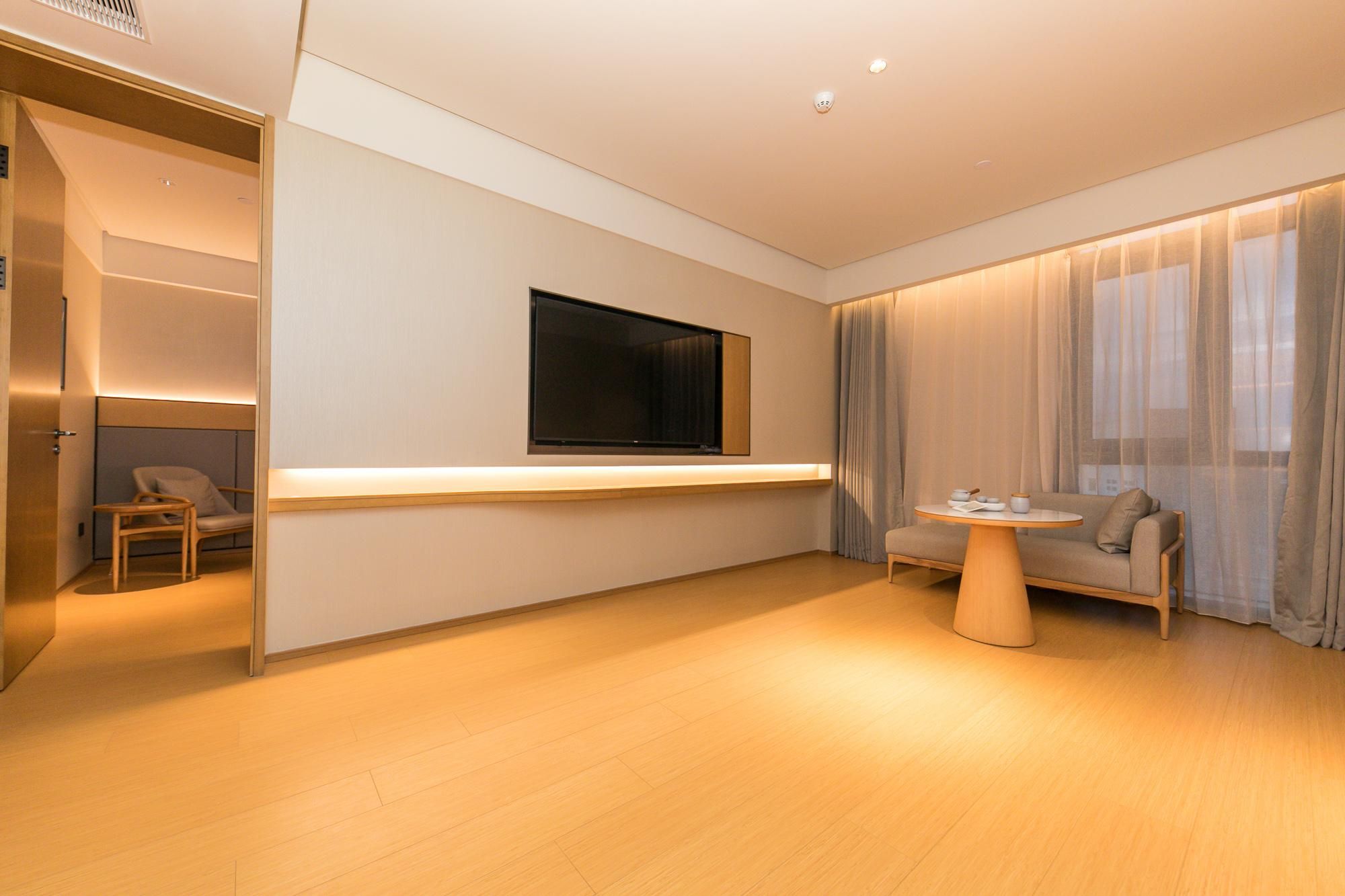 Uma sala de estar moderna com um sofá, uma mesa de centro, uma TV na parede e um guarda-roupa com portas de correr.