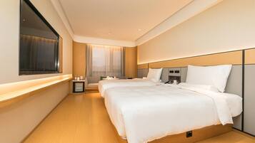 Una habitación de hotel moderna con dos camas, un televisor, una mesita de noche con lámpara y una ventana con cortinas.