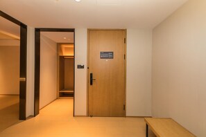 A hallway with a wooden door, a bench, and a light switch on the wall. - Ji Hotel (nanjing Jiangning Southeast University s (Nanjing)