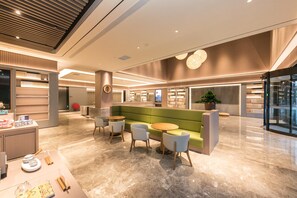A modern lobby with a green sofa, round tables, and a display of kitchenware. - Ji Hotel (nanjing Jiangning Southeast University s (Nanjing)