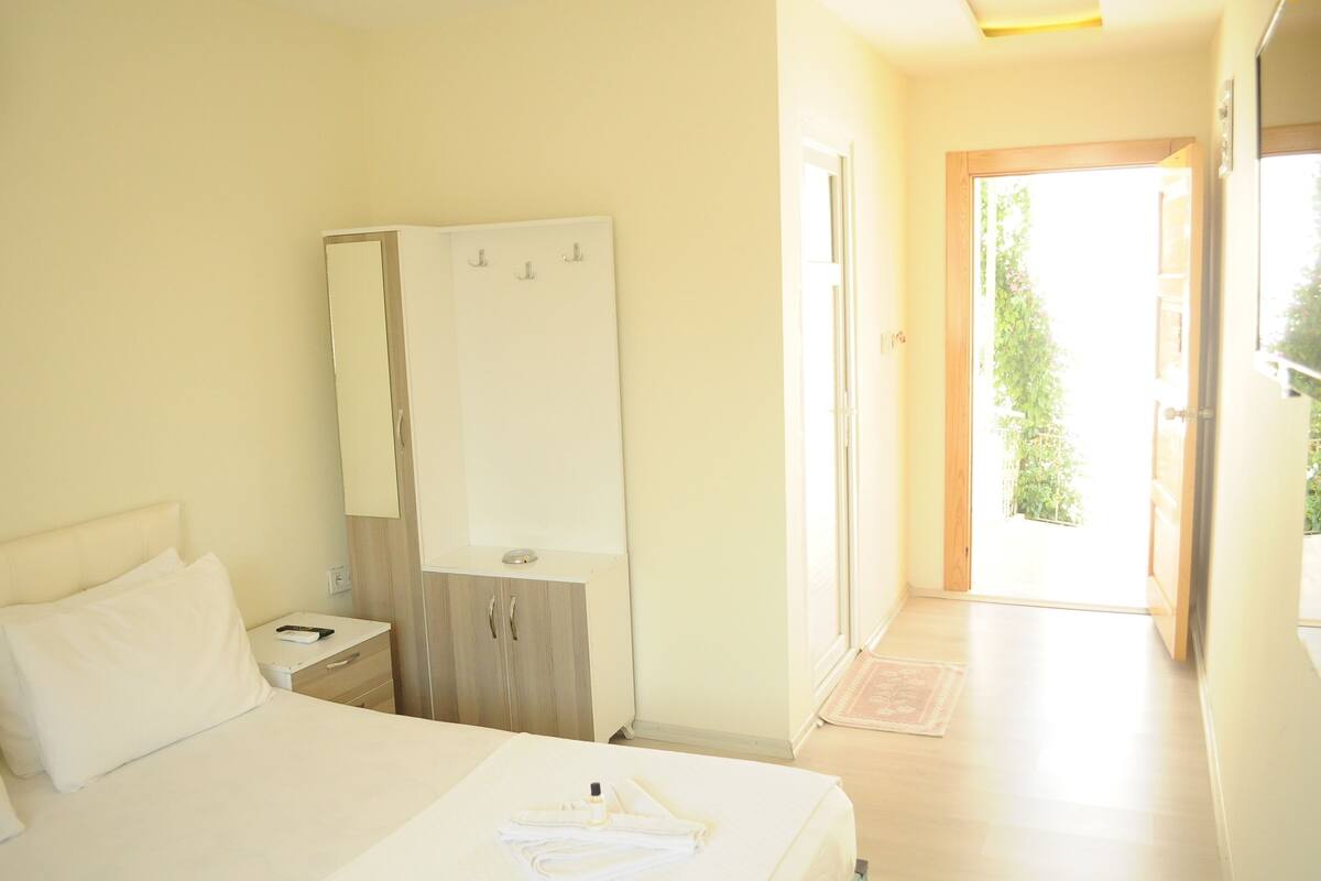Una habitación de hotel con cama, armario, mesita de noche y puerta que da a un balcón.