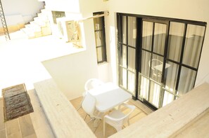 A white outdoor seating area with a table and chairs, a window with blinds, and a staircase. - Kemer Suit (Kemer)