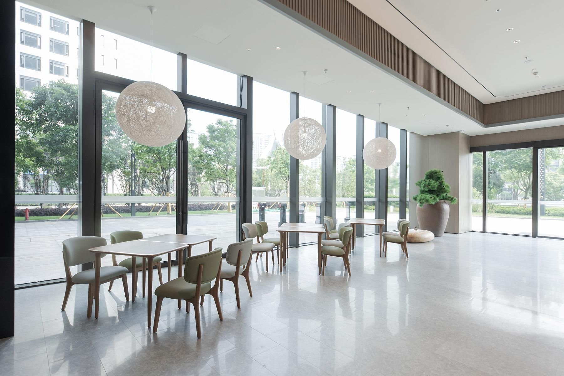 Un amplio espacio interior con ventanas grandes, muebles modernos y una planta en maceta.