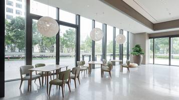 Un amplio espacio interior con ventanas grandes, muebles modernos y una planta en maceta.