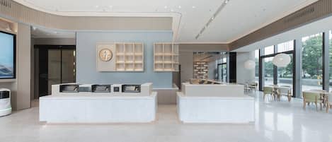 Un moderno vestíbulo de hotel con mostrador de recepción, zona de estar y ventanas amplias.
