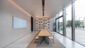 A modern conference room with a long table, chairs, a bookshelf, and large windows. - Ji Hotel (Wuhan)