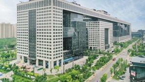 A modern high-rise building with a glass facade, surrounded by greenery and a busy street. - Ji Hotel (Wuhan)