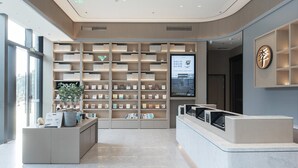 A modern reception area with a large bookshelf, a digital screen, and a reception desk. - Ji Hotel (Wuhan)