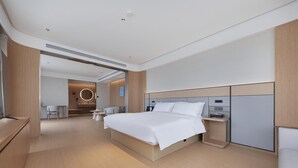 A modern hotel room with a large bed, bedside tables, a desk, and a seating area. - Ji Hotel (Wuhan)